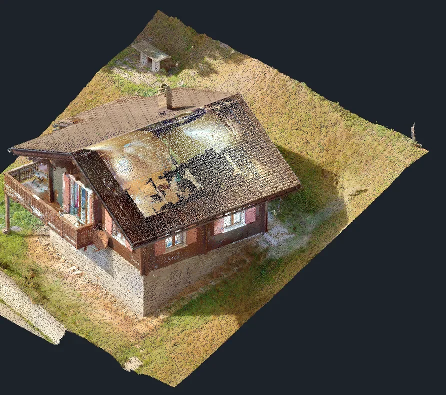 Dichte farbige Punktewolke einer Schweizer Alphütte schräg von oben: Satteldach mit Kamin, Holzfassade mit Fensterläden, Balkon auf Stützen und das umgebende Wiesengelände. Lücken und einzelne Punkte bleiben sichtbar.