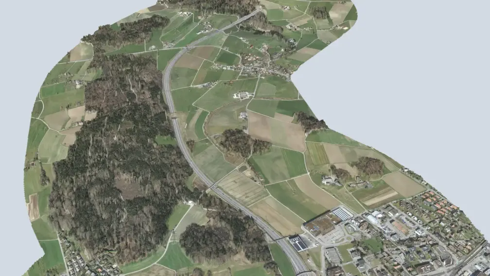 Derselbe Korridor aus derselben Kamera, nun mit dem Luftbild belegt: Felder, Waldstücke, die Autobahn mit Brücke und am unteren Rand ein Ortsteil mit Gewerbebauten.